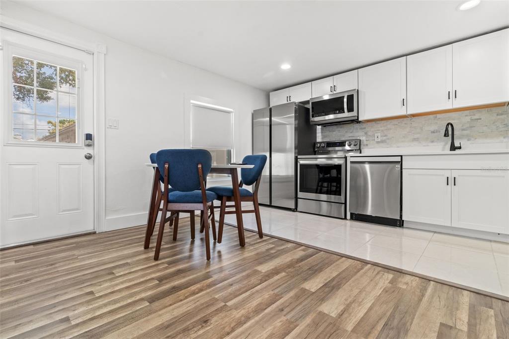 A kitchen with white cabinets, stainless steel appliances, and a small dining table with chairs — 609 N OSCEOLA AVENUE UNIT A, CLEARWATER, FL