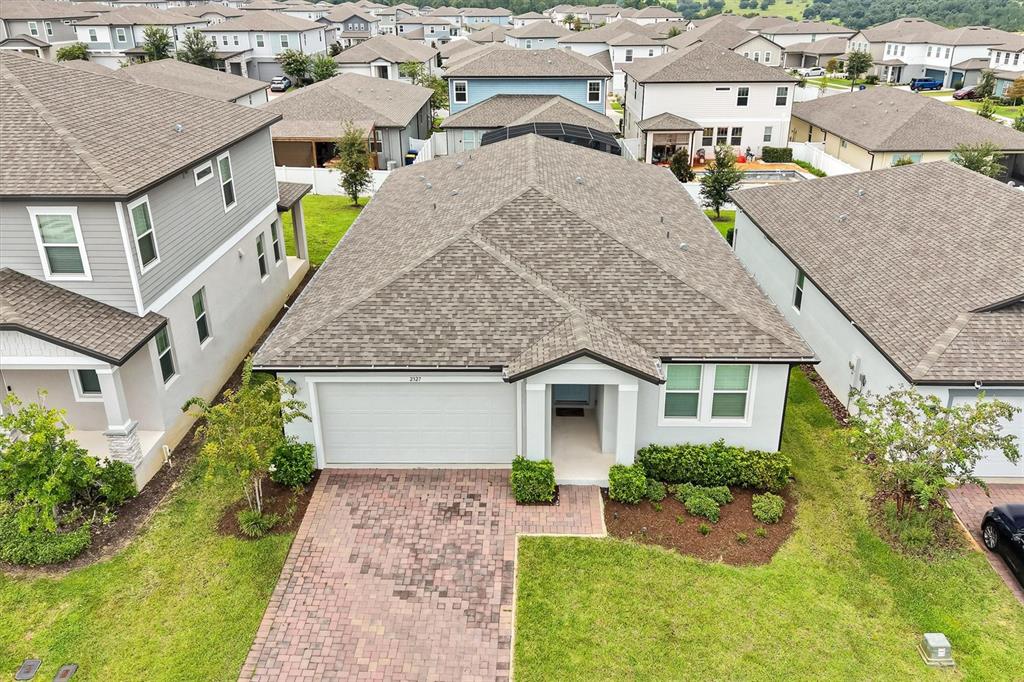 An aerial view shows a single-story house with a brick driveway and a shingled roof — 2327 RAVEN RIDGE ROAD, MINNEOLA, FL