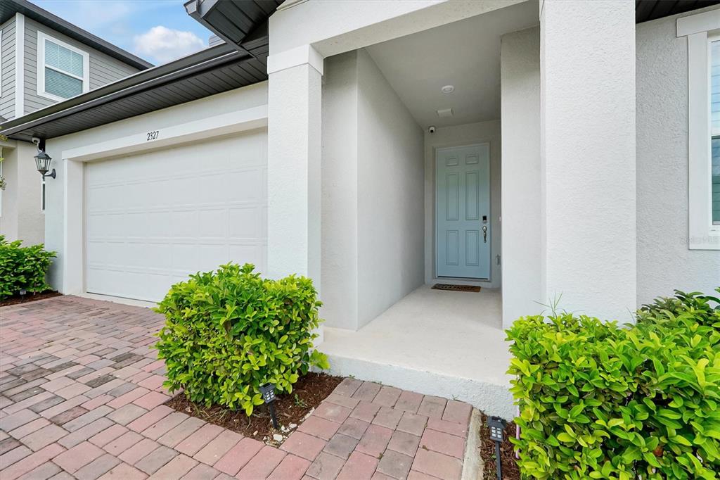 A light blue front door is recessed under a covered entryway next to a garage — 2327 RAVEN RIDGE ROAD, MINNEOLA, FL