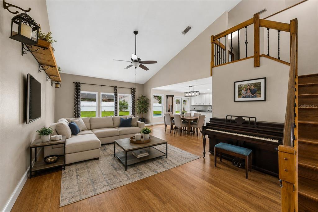 A foyer with wood flooring and a staircase leads to an open living area with vaulted ceilings — 1714 CYPRESS RIDGE DRIVE, ORLANDO, FL