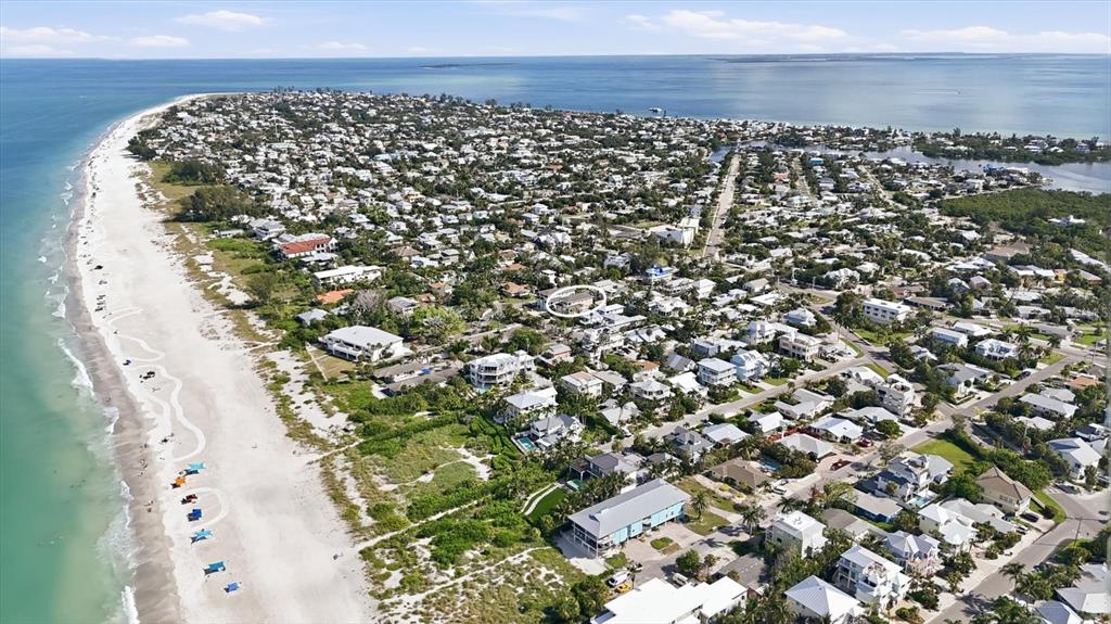 An aerial view shows a coastal neighborhood with houses situated along a sandy beach — 113 AQUA LANE, HOLMES BEACH, FL