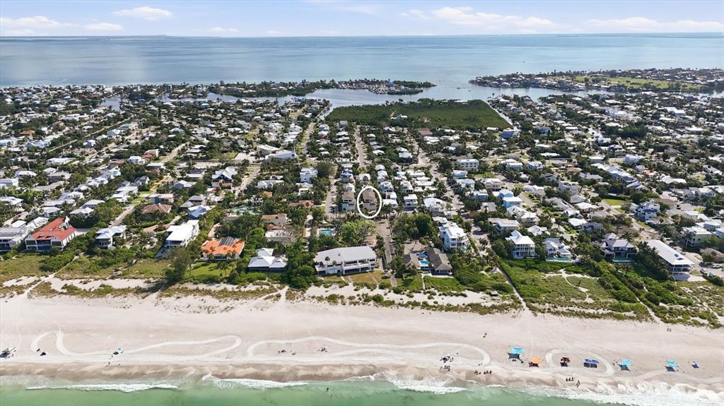 An aerial view shows a coastal neighborhood with a white circle highlighting a specific house — 113 AQUA LANE, HOLMES BEACH, FL