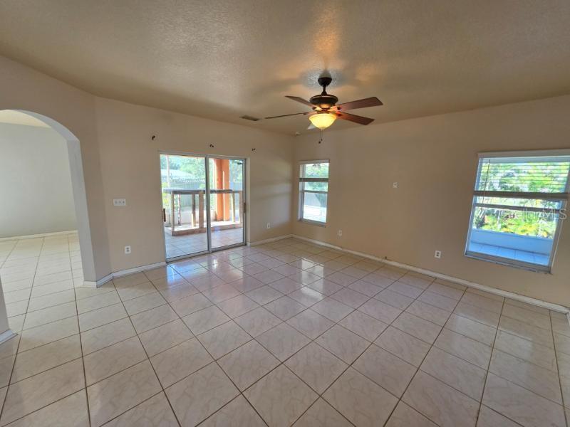 A spacious living room features light tile flooring, a ceiling fan, and sliding glass doors — 731 CRISTELLE JEAN DRIVE, RUSKIN, FL