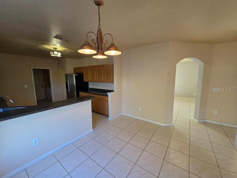 A kitchen with wooden cabinets and a breakfast bar overlooks a tiled dining area — 731 CRISTELLE JEAN DRIVE, RUSKIN, FL