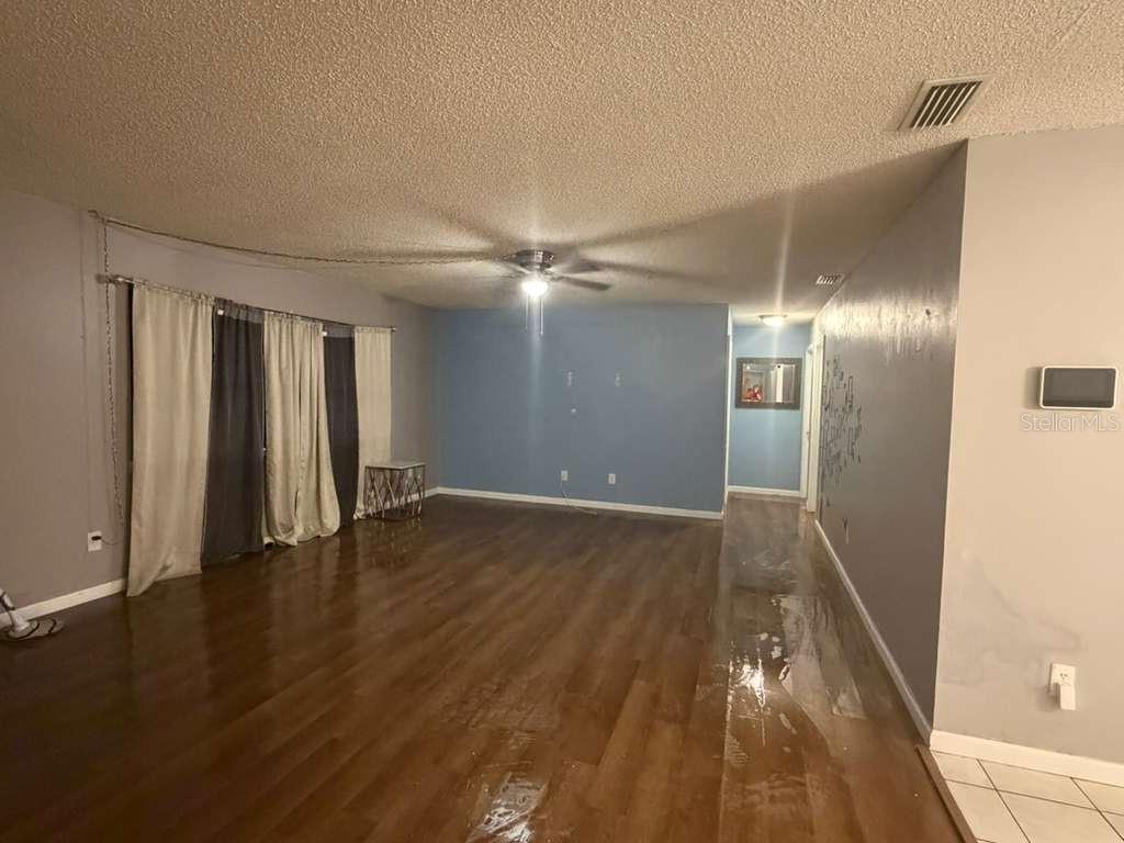 A living room with wood-look flooring, a ceiling fan, and blue accent walls — 2824 W HURON DRIVE, DELTONA, FL