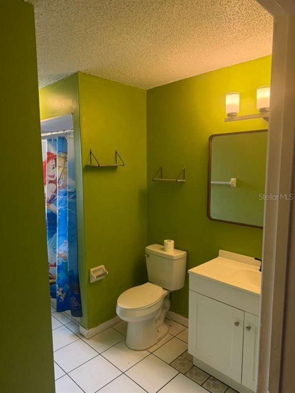 A bathroom features lime green walls, a white vanity, a toilet, and a mermaid shower curtain — 2824 W HURON DRIVE, DELTONA, FL