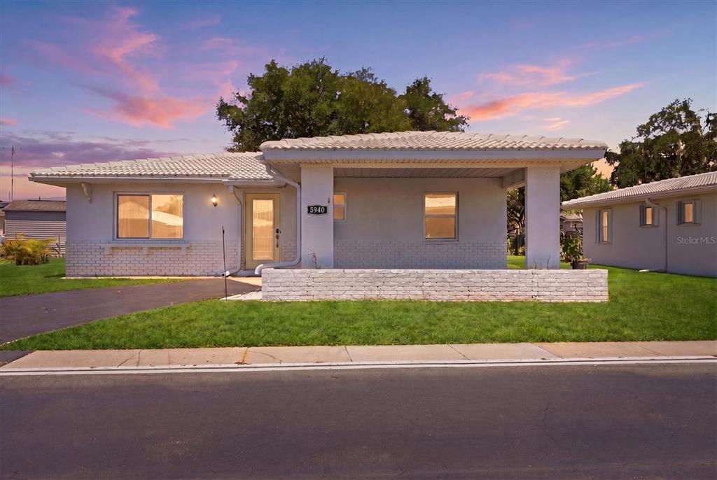 A single-story house with a white brick facade, a covered porch, and a tiled roof — 8940 PICKWICK ROAD, NORTH PORT, FL