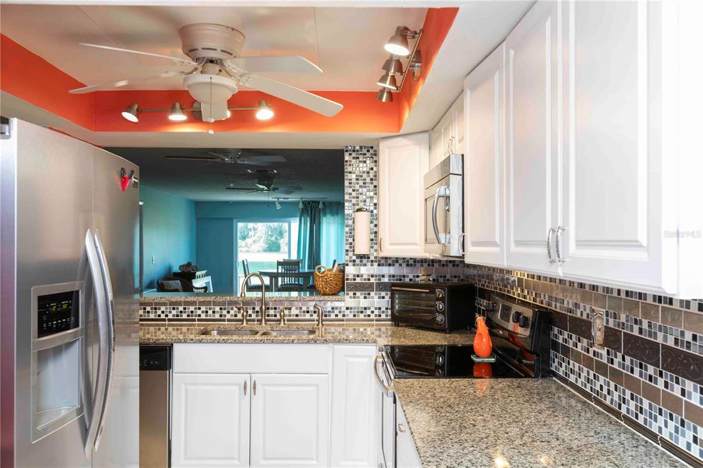 A kitchen with white cabinets, granite countertops, a mosaic tile backsplash, and stainless steel appliances — 9639 GREENSKEEPER DRIVE UNIT 9639, NEW PORT RICHEY, FL