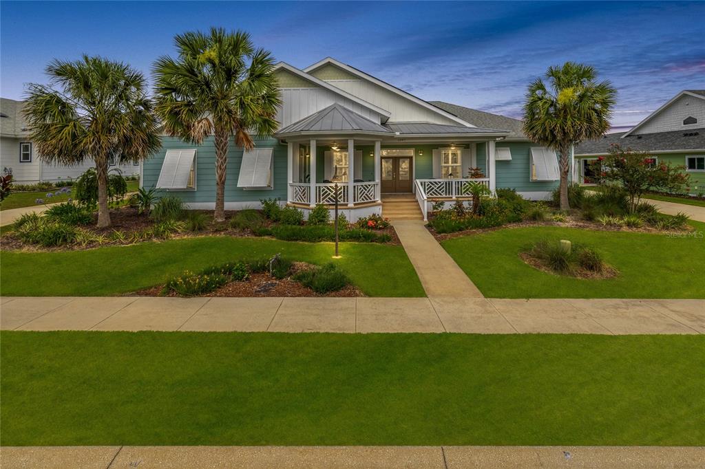 A light blue single-story house with a front porch and palm trees in the yard — 1097 SUGAR LOAF KEY LOOP, LADY LAKE, FL