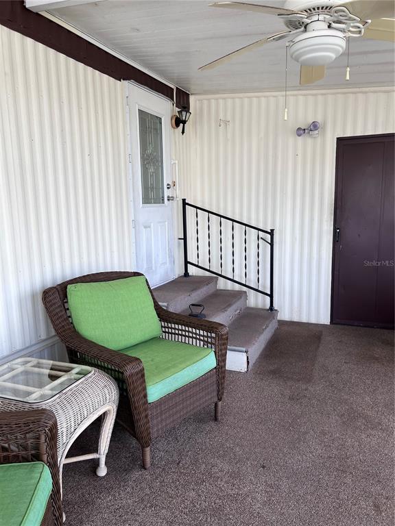 A covered porch features a wicker chair with green cushions, stairs with a railing, and a ceiling fan — 3326 DENISE DRIVE, ELLENTON, FL