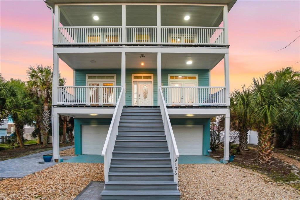 A three-story coastal home features a central staircase leading to a covered porch and balcony — 9106 MELLON COURT, ST AUGUSTINE, FL