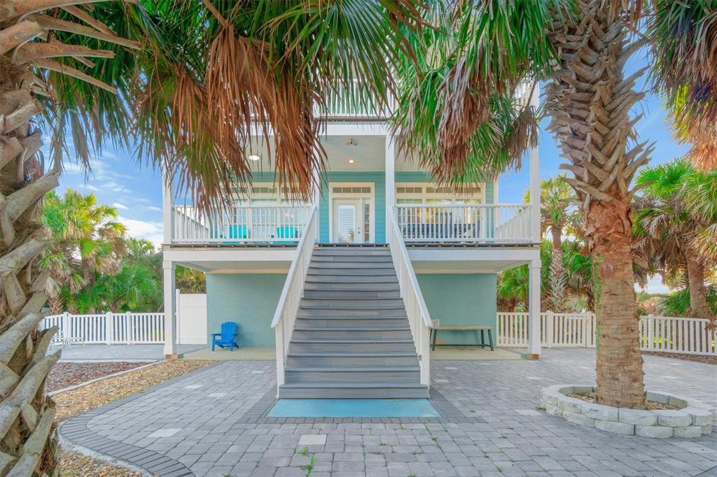 A stilt house with a central staircase leading to a raised porch and paved patio — 9106 MELLON COURT, ST AUGUSTINE, FL