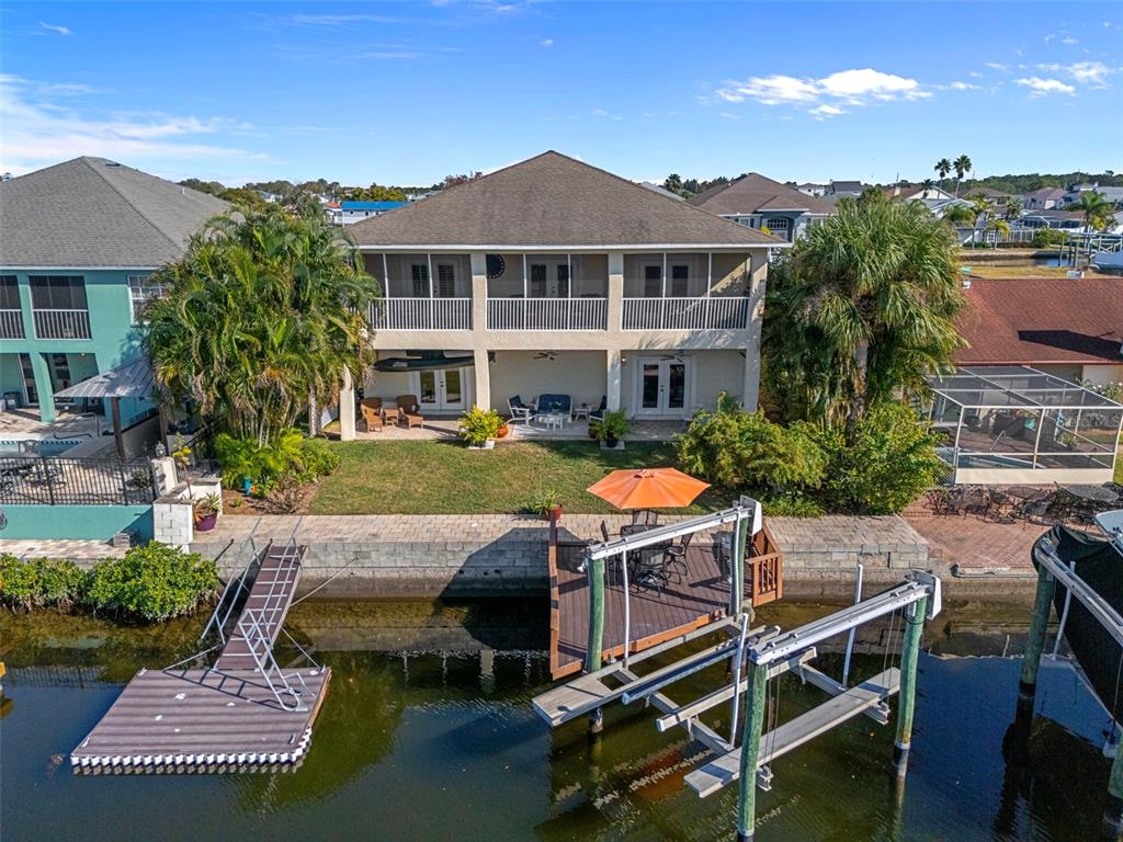 A two-story waterfront house features a screened balcony, a patio, and a private boat dock — 15631 ALLMAND DRIVE, HUDSON, FL