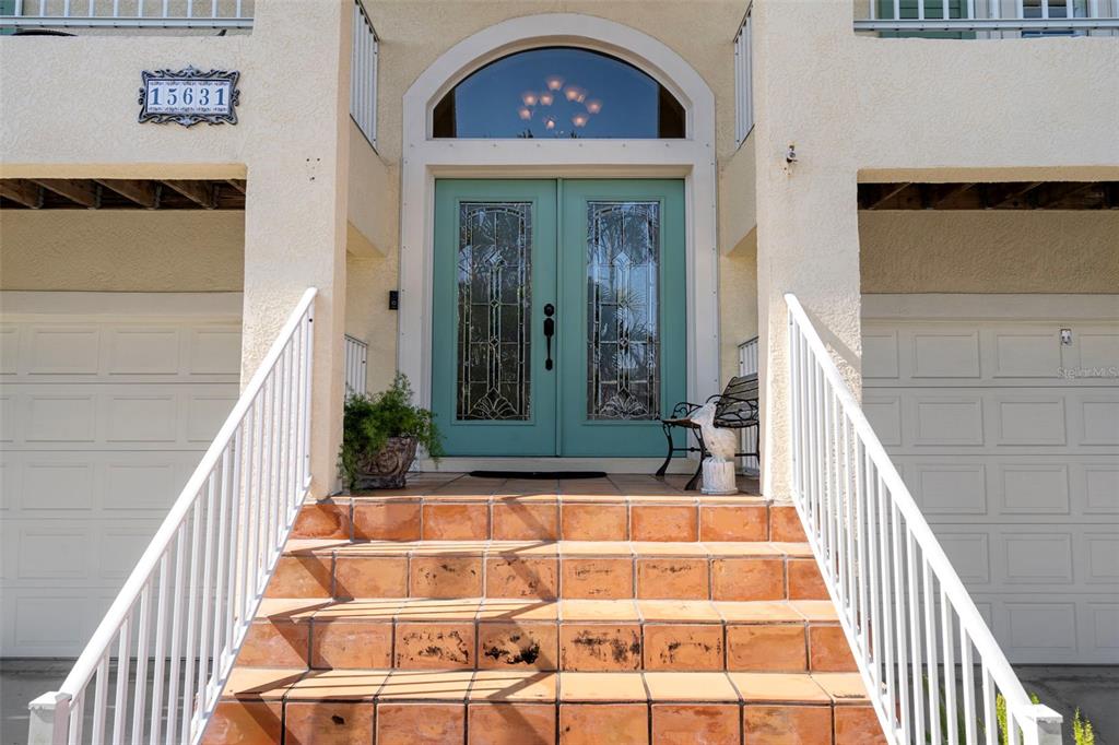 A set of stairs leads to a teal double front door with glass inserts — 15631 ALLMAND DRIVE, HUDSON, FL