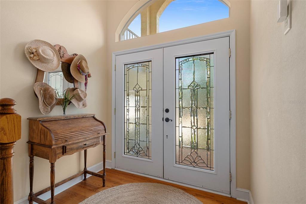 An entryway features a wooden roll-top desk, a wall-mounted hat rack, and double glass-paneled doors — 15631 ALLMAND DRIVE, HUDSON, FL
