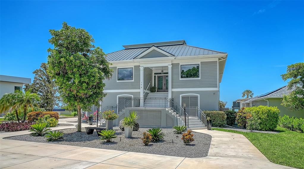 A two-story house with gray siding, a metal roof, and a raised front entrance — 7418 WESTMORELAND DRIVE, SARASOTA, FL