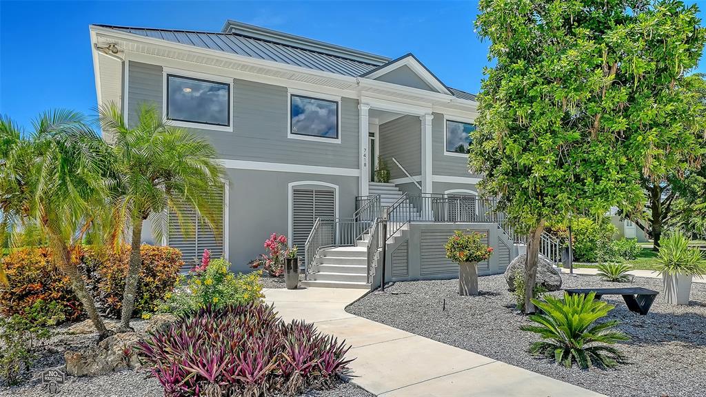 A two-story house with gray siding, a metal roof, and a raised front entrance staircase — 7418 WESTMORELAND DRIVE, SARASOTA, FL