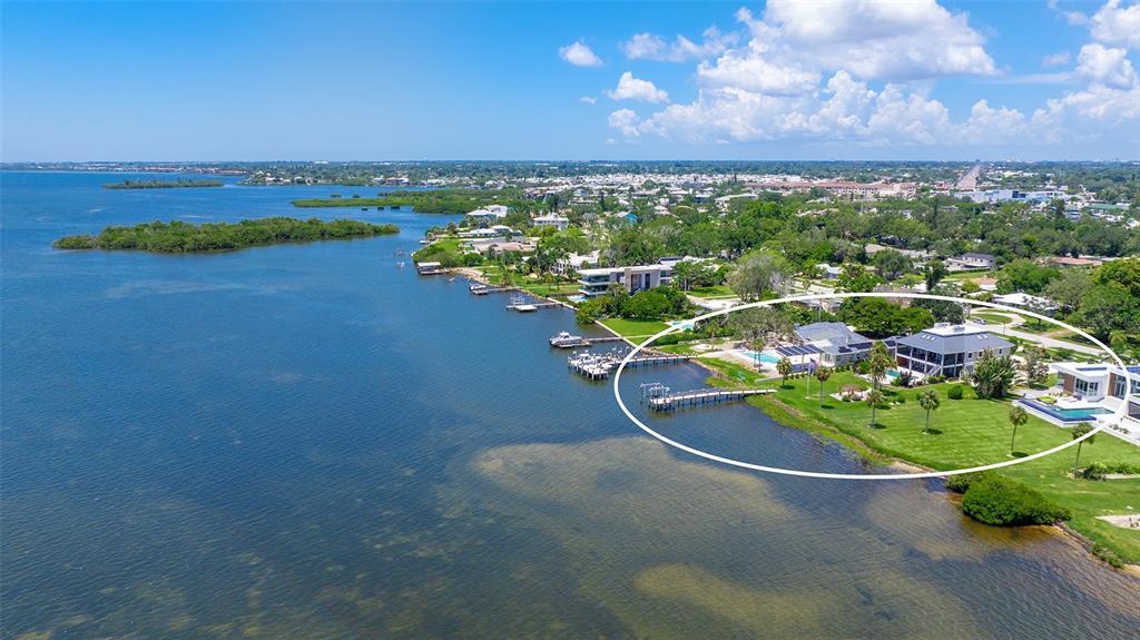 An aerial view shows a waterfront property with a large lawn, dock, and swimming pool — 7418 WESTMORELAND DRIVE, SARASOTA, FL