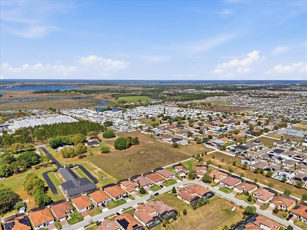 An aerial view shows a suburban neighborhood with houses featuring tiled roofs and screened-in pools — 363 VILLA SORRENTO CIRCLE, HAINES CITY, FL