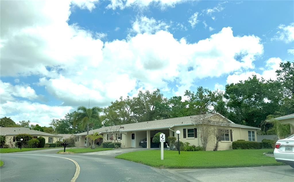 A single-story residential building with a carport and a lawn under a cloudy sky — 390 301 BOULEVARD W UNIT 8A, BRADENTON, FL