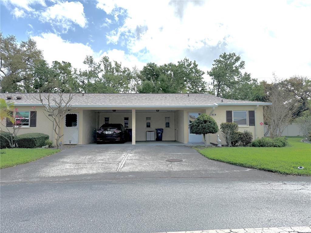 A single-story duplex features a shared carport, two front doors, and a paved driveway — 390 301 BOULEVARD W UNIT 8A, BRADENTON, FL