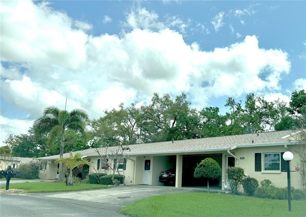 A single-story residential building features a beige exterior, a covered carport, and a grassy lawn — 390 301 BOULEVARD W UNIT 8A, BRADENTON, FL