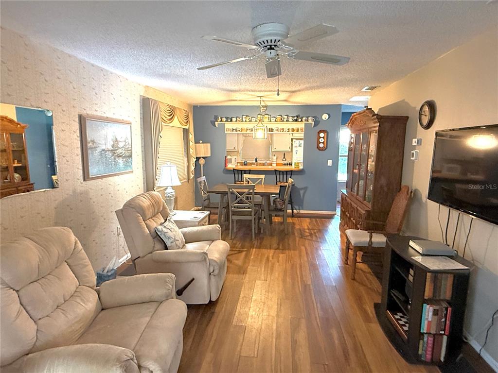A living room with wood flooring, a ceiling fan, and an adjacent dining area — 390 301 BOULEVARD W UNIT 8A, BRADENTON, FL