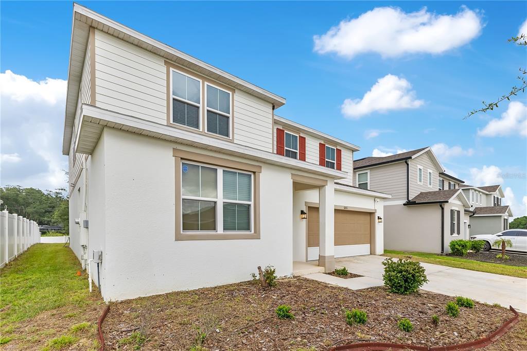 A two-story house with white siding, a tan garage, and a small front yard — 686 HERITAGE SQUARE DRIVE, HAINES CITY, FL