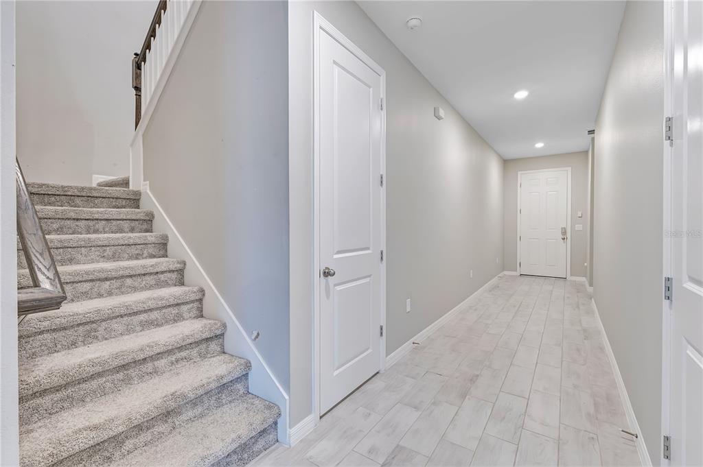 A hallway features light-colored tile flooring, gray walls, a carpeted staircase, and two white doors — 686 HERITAGE SQUARE DRIVE, HAINES CITY, FL