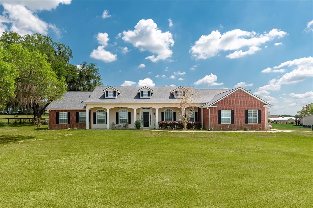 A single-story brick house with a covered front porch and three dormer windows — 13025 NW GAINESVILLE ROAD, REDDICK, FL