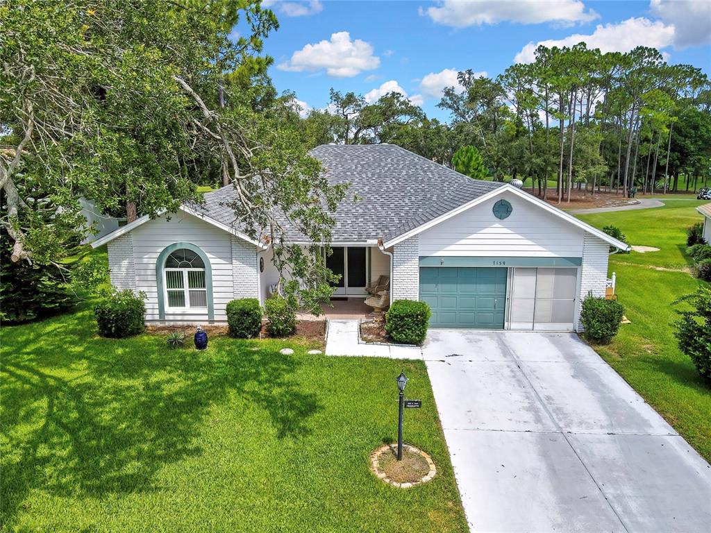 An aerial view of a single-story house with a white exterior, gray roof, and driveway — 7159 CROWN OAKS DRIVE, SPRING HILL, FL