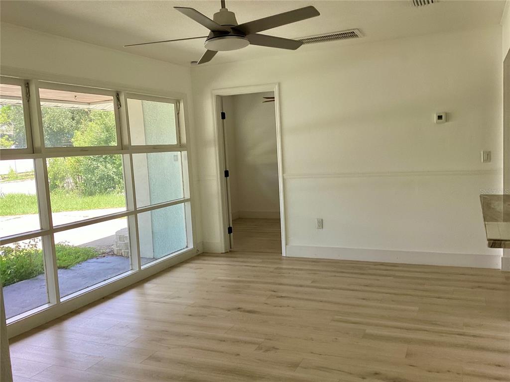 A bright room with light wood-look flooring, a ceiling fan, and large windows — 2370 BAHIA VISTA STREET, SARASOTA, FL