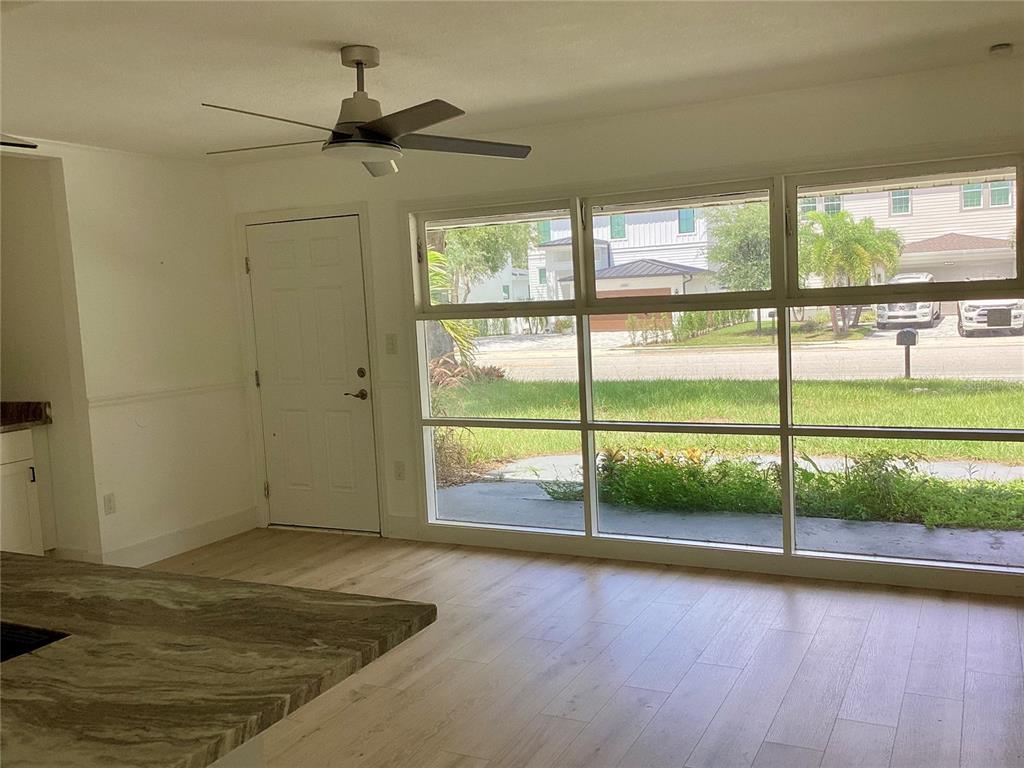 A room with light wood flooring, a ceiling fan, and large windows overlooking a street — 2370 BAHIA VISTA STREET, SARASOTA, FL