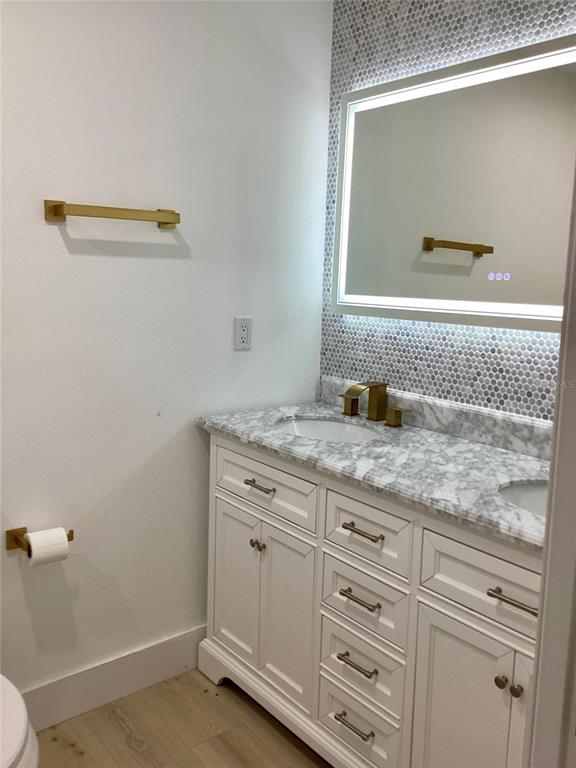 A bathroom features a white vanity with marble countertop, gold hardware, and a backlit mirror — 2370 BAHIA VISTA STREET, SARASOTA, FL