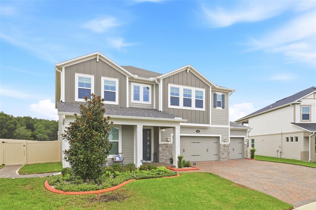 A two-story house with gray siding, a stone-accented entryway, and a paved driveway — 806 CREEPING FIG STREET, APOPKA, FL