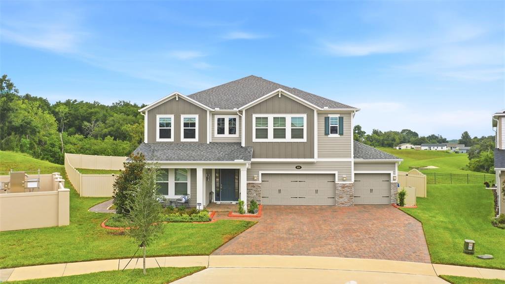 A two-story suburban house features a brick driveway, a three-car garage, and gray siding — 806 CREEPING FIG STREET, APOPKA, FL