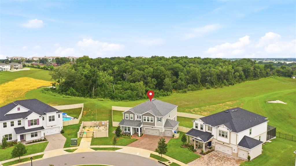 An aerial view shows three suburban houses with gray roofs situated near a large wooded area — 806 CREEPING FIG STREET, APOPKA, FL