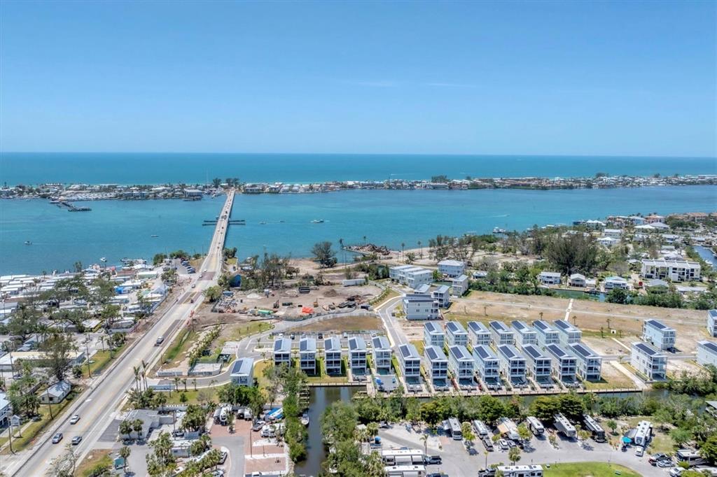An aerial view shows a coastal neighborhood with a bridge, waterfront homes, and RV park — 4357 MARINA VIEW WAY, CORTEZ, FL
