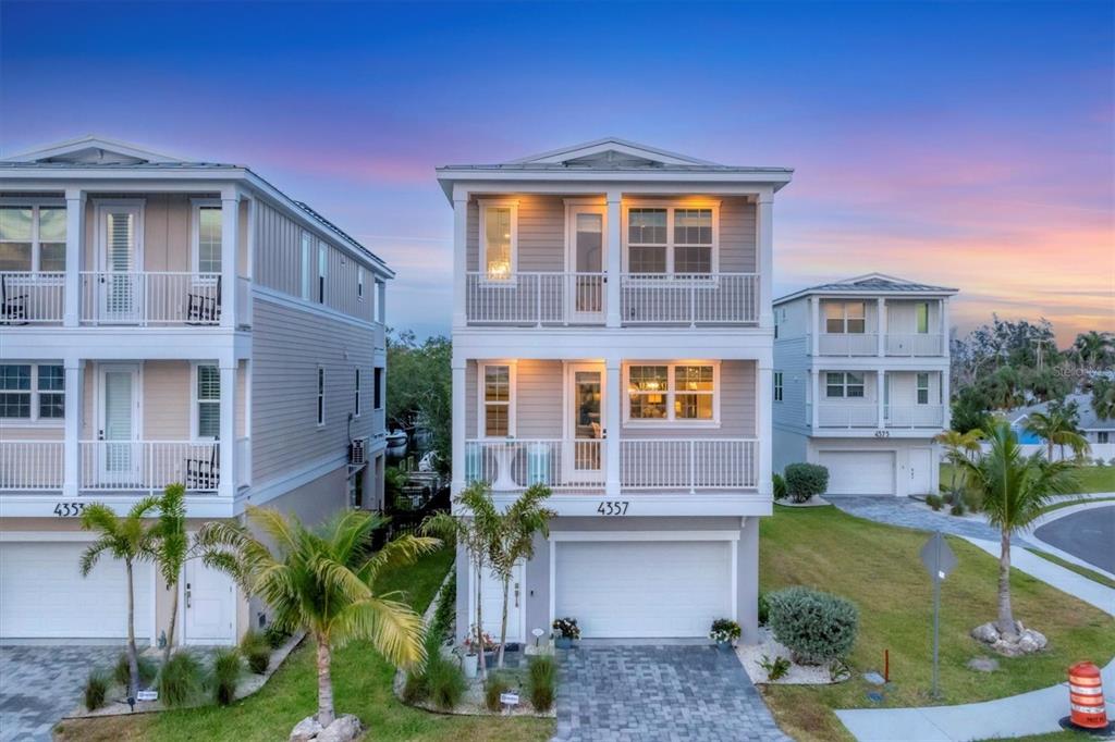 An exterior view of a three-story coastal home with balconies and a paved driveway — 4357 MARINA VIEW WAY, CORTEZ, FL
