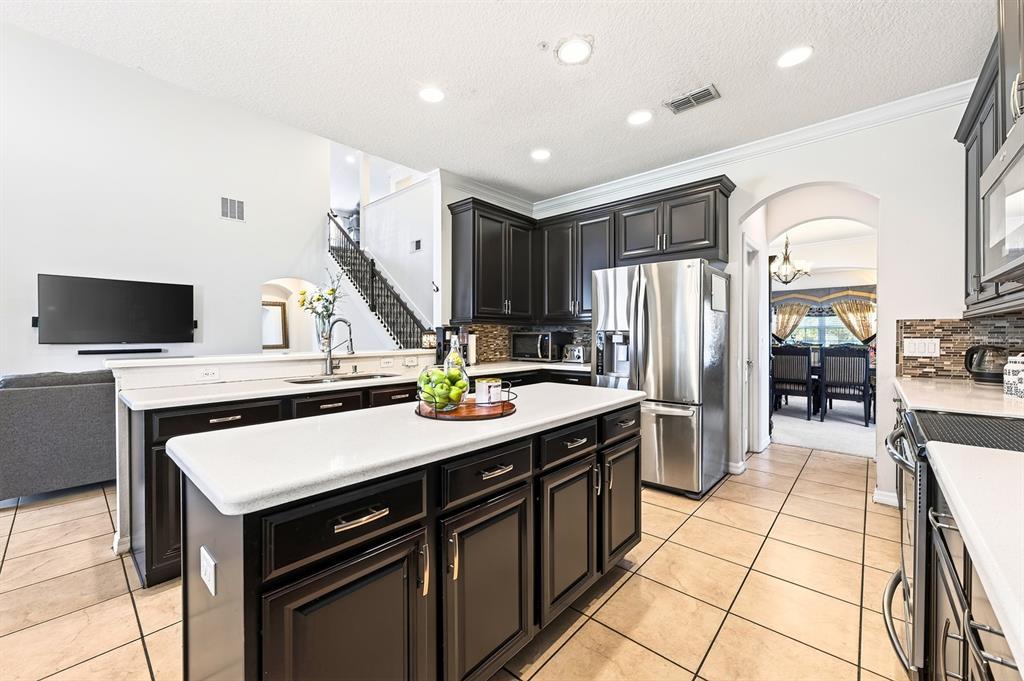 A kitchen features dark wood cabinets, a white island countertop, and stainless steel appliances — 12834 BOGGY VIEW DRIVE, ORLANDO, FL