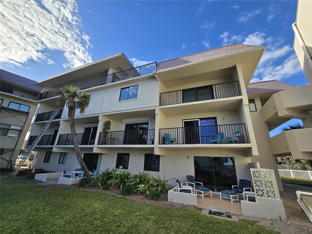The exterior of a multi-story residential building features balconies, sliding glass doors, and a palm tree — 935 OCEAN SHORE BOULEVARD UNIT 3040, ORMOND BEACH, FL