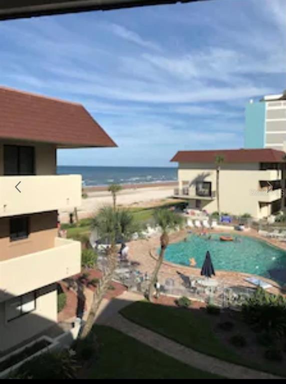 An elevated view of a swimming pool, beach, and ocean from a balcony — 935 OCEAN SHORE BOULEVARD UNIT 3040, ORMOND BEACH, FL