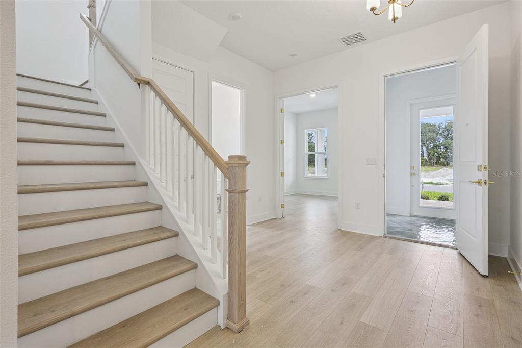An entryway features a teal shiplap wall, a wooden console table, and a red door — 17434 HONEYBELL TANGELO COURT, WINTER GARDEN, FL