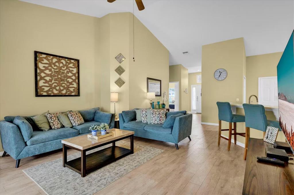 A living room features two blue sofas, a coffee table, and a breakfast bar area — 1208 CEDARWOOD WAY, CLERMONT, FL