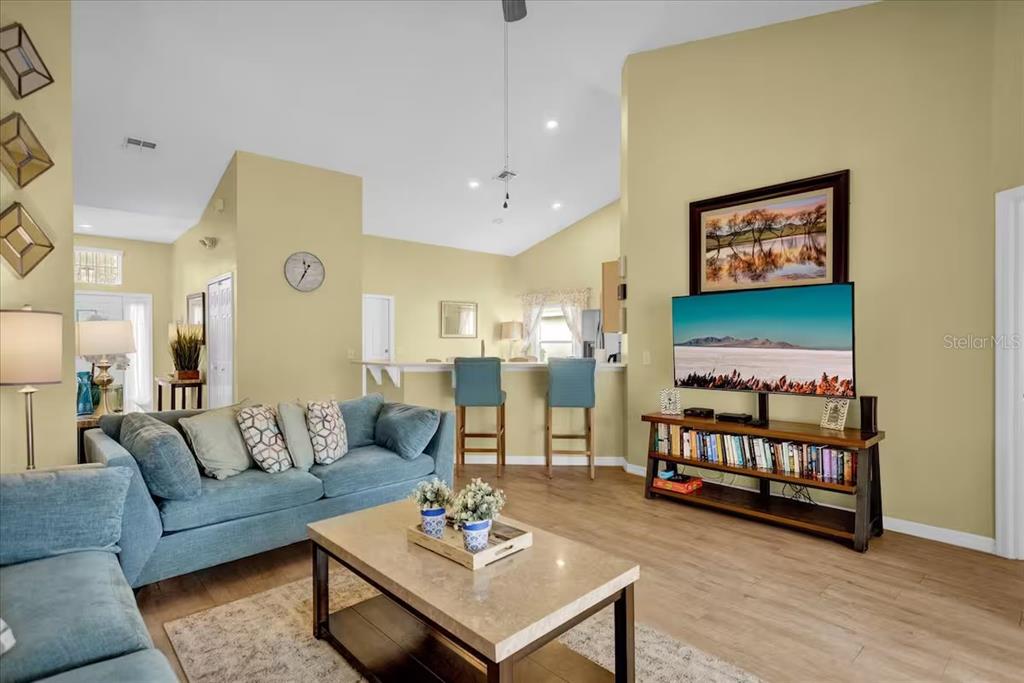 A living room features a blue sofa, a coffee table, and a television on a stand — 1208 CEDARWOOD WAY, CLERMONT, FL
