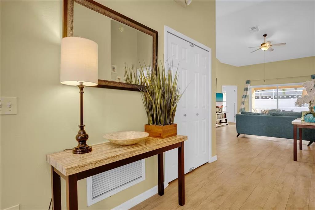 A foyer features a console table, lamp, mirror, and a view into a living area — 1208 CEDARWOOD WAY, CLERMONT, FL