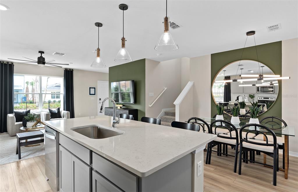 A kitchen island with a sink sits in front of a dining area and living room — 16681 SILVER BROOK WAY, WINTER GARDEN, FL