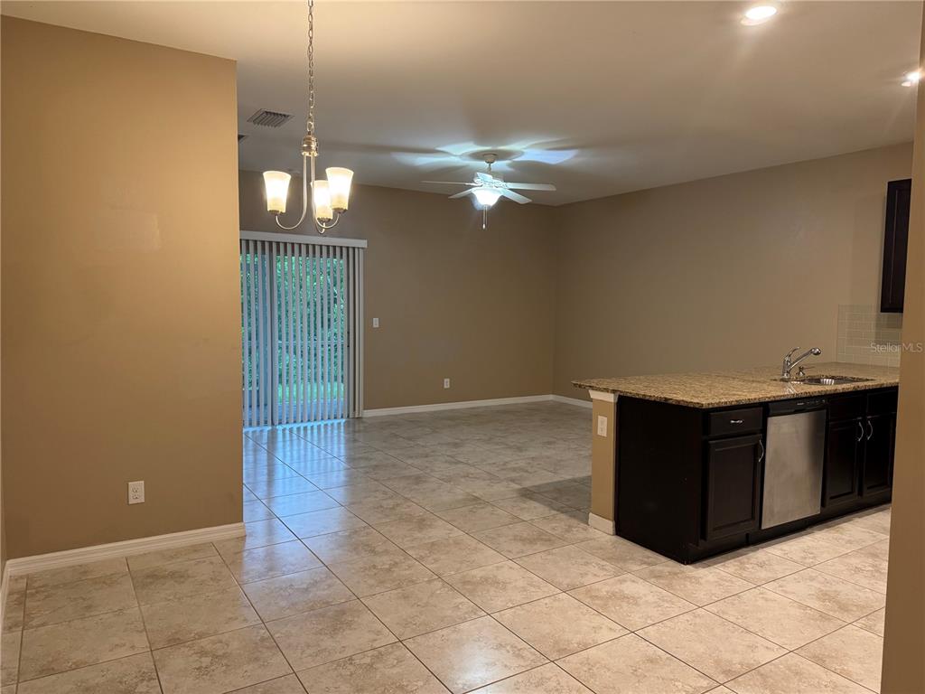A kitchen with dark cabinets and granite countertops overlooks an open dining and living area — 26077 SANDHILL BOULEVARD, PUNTA GORDA, FL