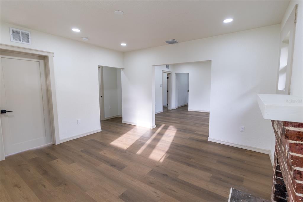 An interior room features white walls, wood-look flooring, recessed lighting, and a brick fireplace — 14022 4TH STREET, DADE CITY, FL