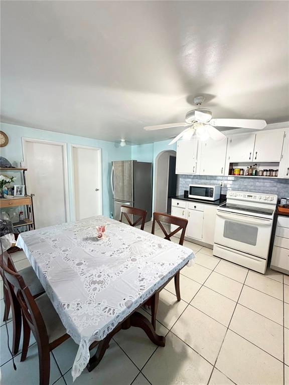 A kitchen and dining area features a white table, tile flooring, and white cabinetry — 8904 N 20TH STREET, TAMPA, FL